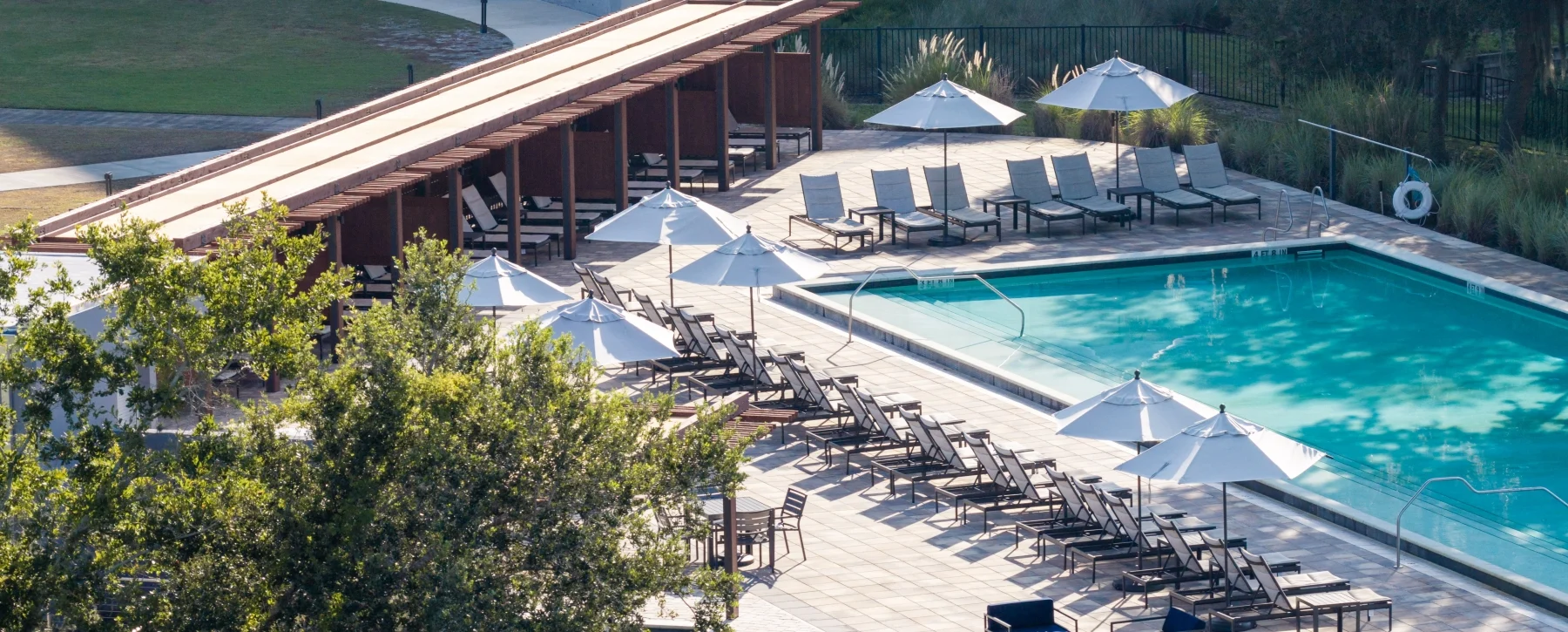 Outdoor pool surrounded by loungers, umbrellas, and cabanas